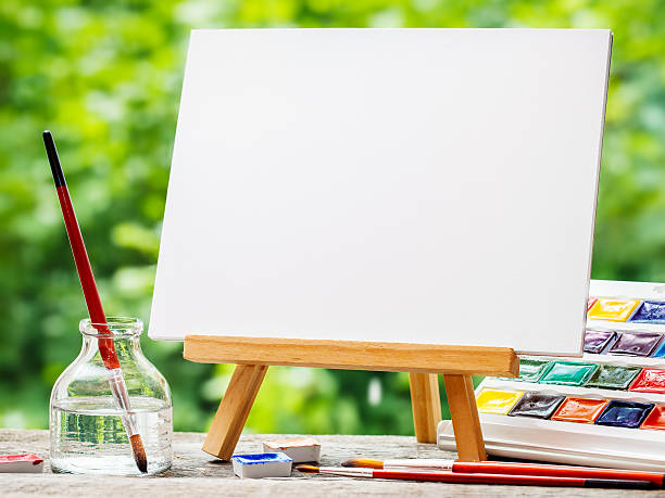 istock Sketchbook on easel, watercolor paints and paintbrushes 593323014
