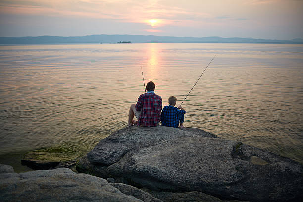 la pêche au coucher du soleil - fishing father son family photos et images de collection