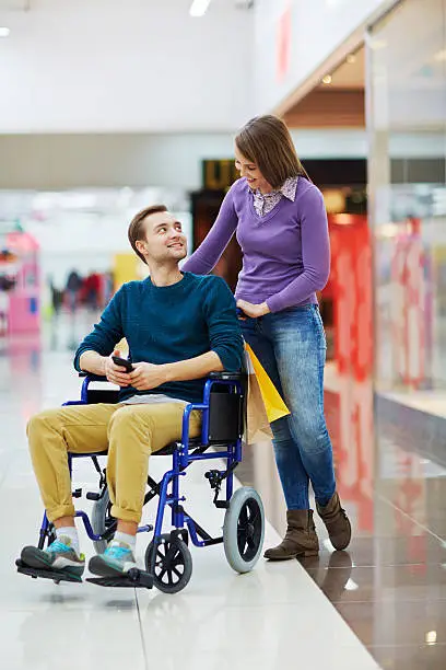 Disabled young man looking at his girlfriend in shopping center