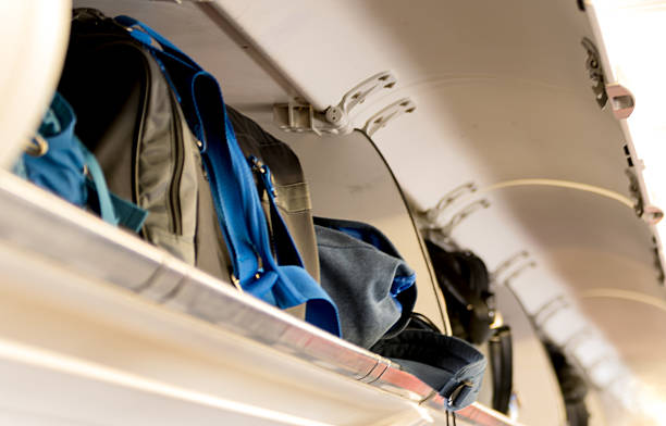 istock Carry on luggage in overhead storage compartment . Airplane cabin interior. 593328856