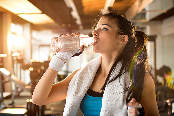 atlético joven mujer agua potable en el gimnasio. - aerobics beautiful bottle body fotograf�ías e imágenes de stock