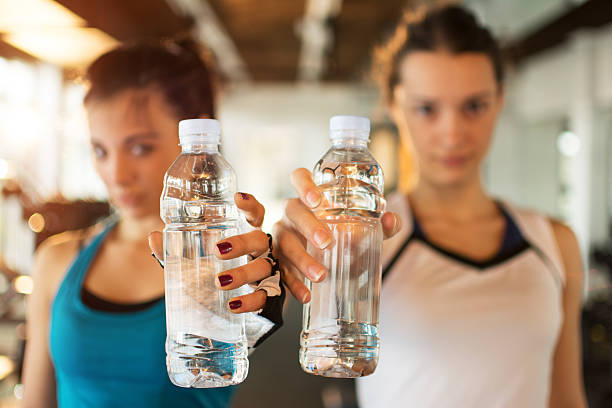 jeunes femmes de fitness avec des bouteilles d’eau. concentrez-vous sur les bouteilles. - beautiful caucasian teenager running photos et images de collection