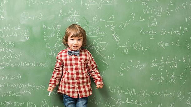 istock Little boy standing in front of green blackboard 593334112