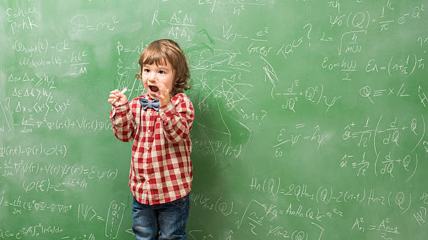 istock Little boy standing in front of green blackboard 593334172