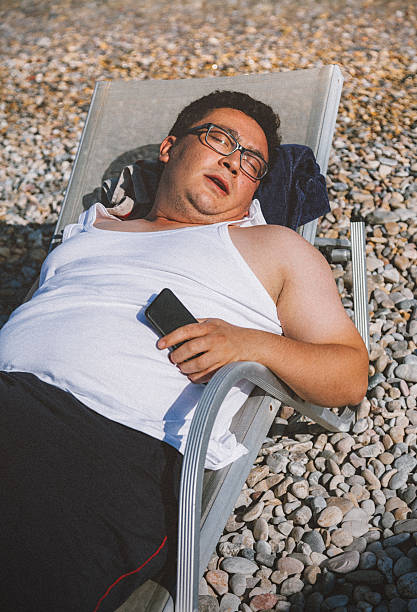 man in chair sunbathing on the beach near the sea - adipose cell imagens e fotografias de stock