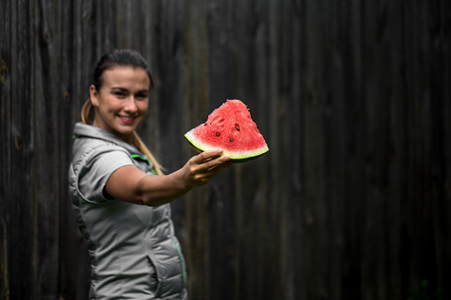 young beautiful girl for a healthy lifestyle, is holding a watermelon on a wooden background