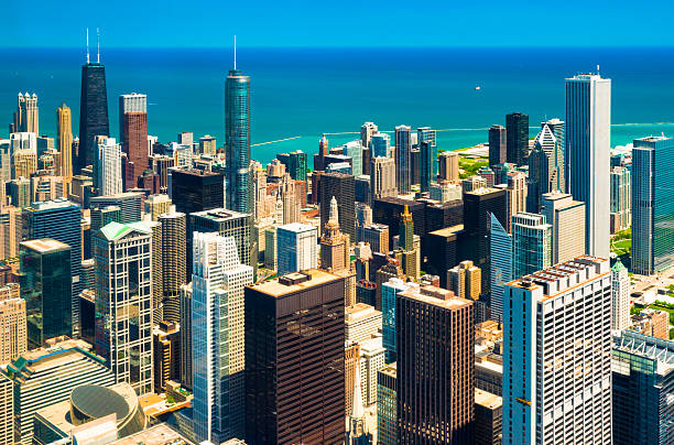 Chicago Downtown Aerial with Blue/Bluegreen Lake Michigan Downtown Chicago skyline aerial view with the John Handcock Center, Trump International Hotel and Tower, and the AON Center, with blue / bluegreen  Lake Michigan and a blue sky in the background.   Shot in a high contrast style. aon center chicago photos stock pictures, royalty-free photos & images