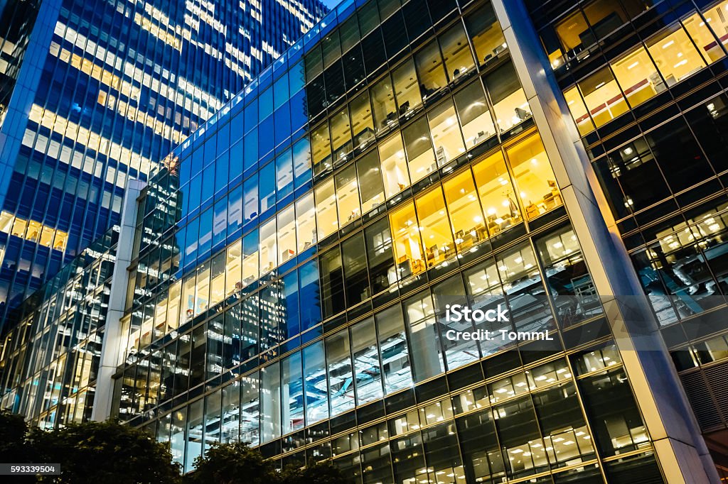 Illuminated office buildings at Canary Wharf, London at Night Illuminated modern office buildings at canary wharf in London at night. Office Building Exterior Stock Photo