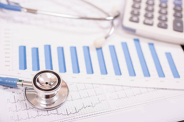 istock Healthcare:  Doctor's stethoscope with EKG and financial bar chart, graph. 593340574