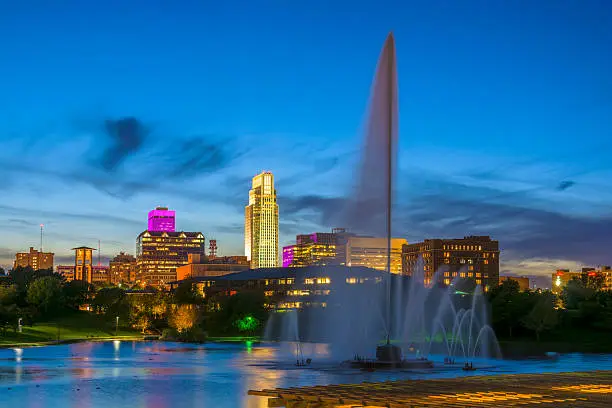 Downtown Omaha skyline with the Heartland of America Park, including a large fountain, in the foreground.