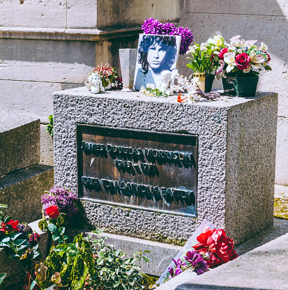 Paris, France - April 27, 2016: Grave of James Douglas (Jim) Morrison with flowers and his photo decorate located at Père Lachaise Cemetery, Paris, France. James Douglas Morrison (1943 – 1971) was an American singer, songwriter, and poet best remembered as the lead singer of the Doors.