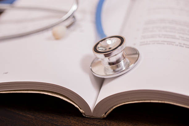 istock Doctor's stethoscope on desk with open books to study, read. 594012230
