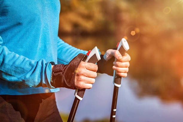 Closeup of woman's hand holding nordic walking poles Nordic walking exercise adventure hiking concept - closeup of woman's hand holding nordic walking poles.  With lens flare and light leaks nordic walking pole stock pictures, royalty-free photos & images