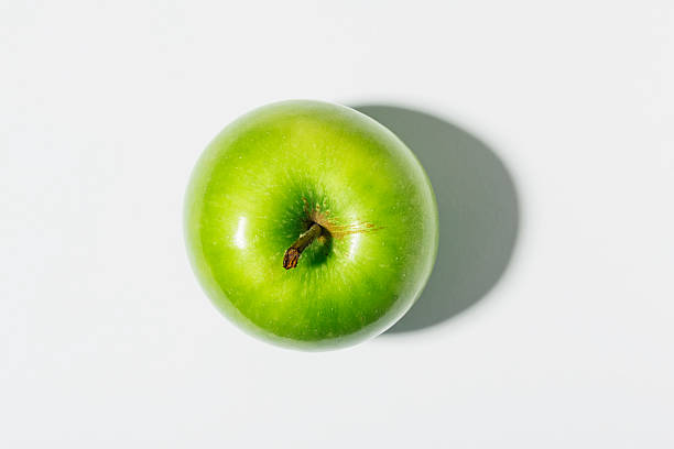 Green Apple against white with strong shadow. stock photo