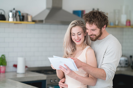 Casual loving couple at home getting the mail and looking happy