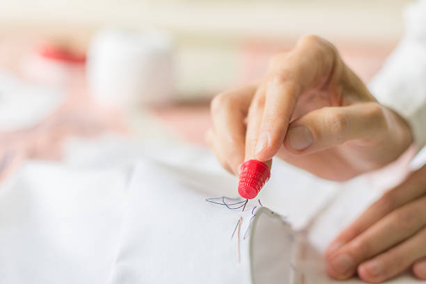 istock Seamstress with thimble on  finger is stiching zipper to  material 594019882