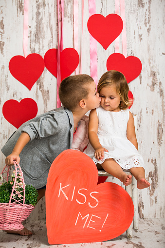 Brother kissing his little sister, giving her present, flower basket