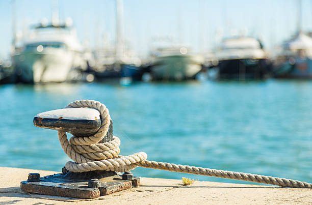 Mooring rope on sea water background Mooring rope and bollard on sea water and yachts background moored stock pictures, royalty-free photos & images