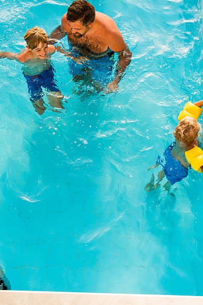 istock Boys and father swimming in pool 594021022