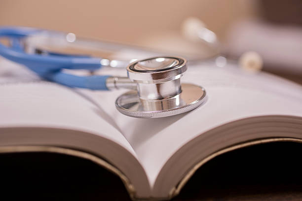 istock Doctor's stethoscope on desk with open books to study, read. 594021554
