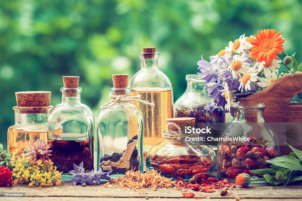 Bottles of tincture or potion and dry healthy herbs Bottles of tincture or potion and dry healthy herbs, bunch of healing herbs in wooden box on table outdoors. Herbal medicine. Retro styled. Herbal Medicine Stock Photo