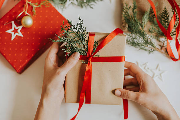 Woman holding Christmas present Decorating Christmas present on the wooden table. christmas human hand christmas ornament decoration stock pictures, royalty-free photos & images