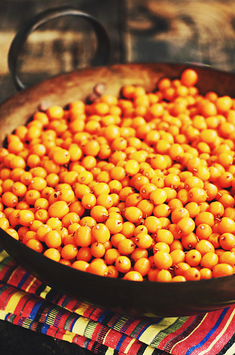 Sea-buckthorn berries in rustic brass bowl, farmhouse style