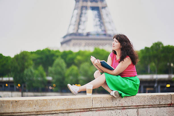 istock Girl with coffee reading a book near the Eiffel tower. 594031528