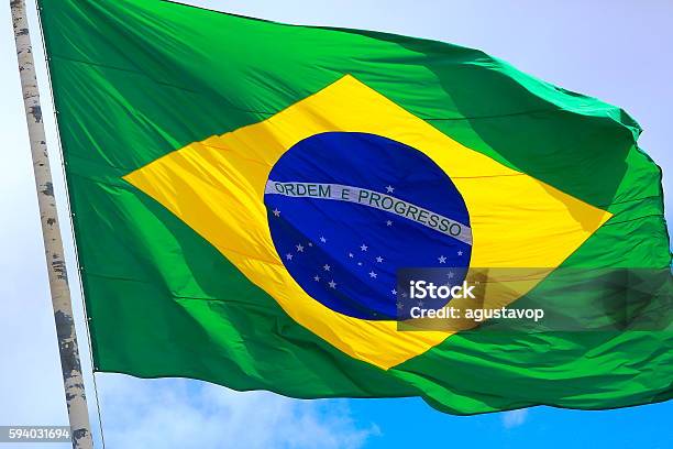 Ordem E Progresso Colorful Brazillian Flag Waving In The Sky Stock Photo - Download Image Now
