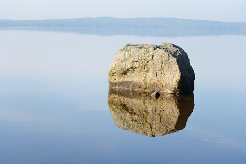 Granite stone in a calm lake with reflection.