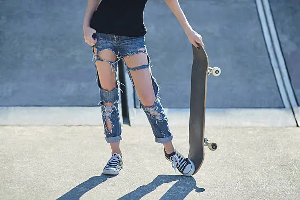 Photo of young woman holding a skateboard