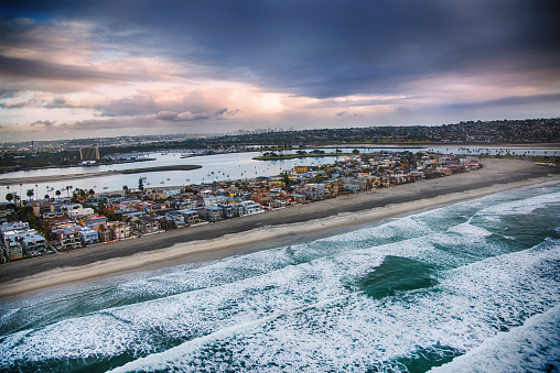 An aerial view of South Mission Beach in San Diego, California with the bay beyond, then downtown in the distance.