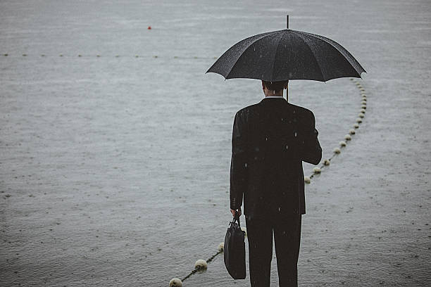 istock Handsome man wearing suit and holding umbrella during the rain 594037862