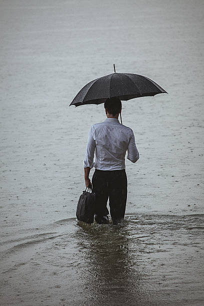 istock Handsome man wearing white shirt and holding umbrella during rain 594037904