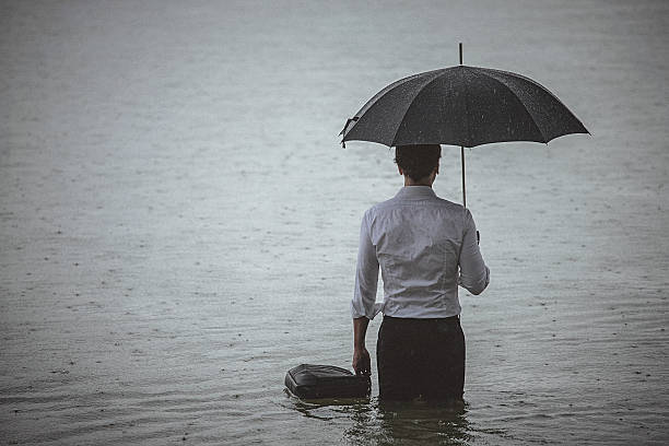 istock Handsome man wearing white shirt and holding umbrella during rain 594037946