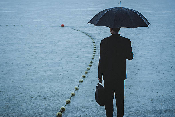 istock Handsome man wearing suit and holding umbrella during the rain 594038002