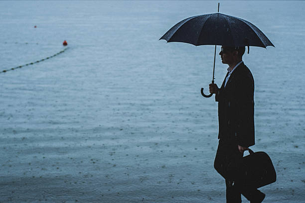 istock Handsome man wearing suit and holding umbrella during the rain 594038060