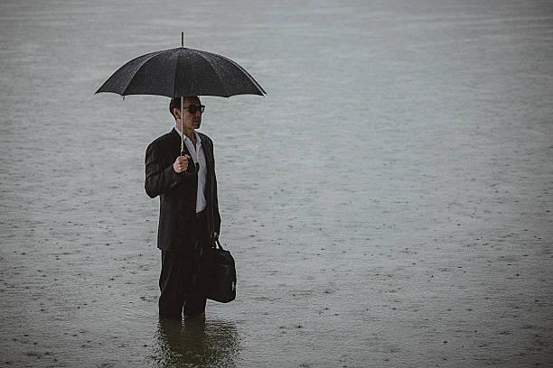 istock Handsome man wearing suit and holding umbrella during the rain 594038150