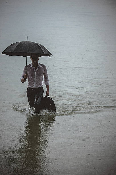 istock Handsome man wearing white shirt and holding umbrella during rain 594038186