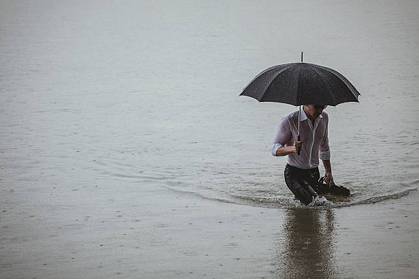 istock Handsome man wearing white shirt and holding umbrella during rain 594038244