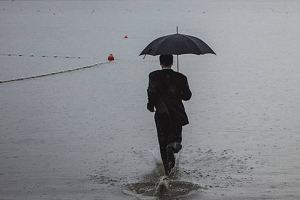 istock Handsome man wearing suit and holding umbrella during the rain 594038294