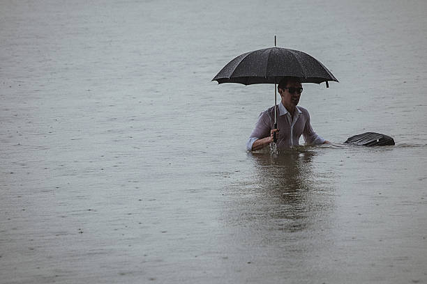 istock Handsome man wearing white shirt and holding umbrella during rain 594038326