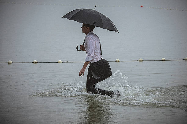 istock Handsome man wearing white shirt and holding umbrella during rain 594038402
