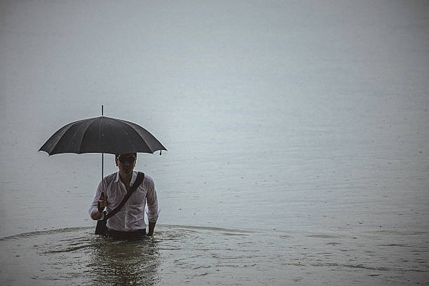 istock Handsome man wearing white shirt and holding umbrella during rain 594038446