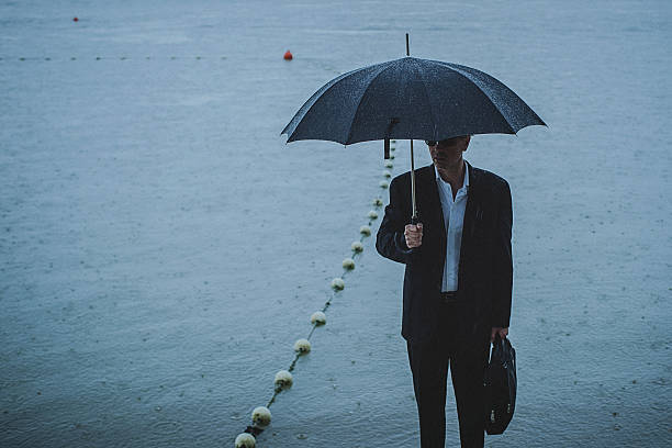 istock Handsome man wearing suit and holding umbrella during the rain 594038528