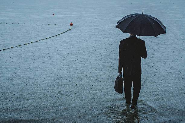 istock Handsome man wearing suit and holding umbrella during the rain 594038622