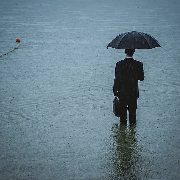 istock Handsome man wearing suit and holding umbrella during the rain 594038686