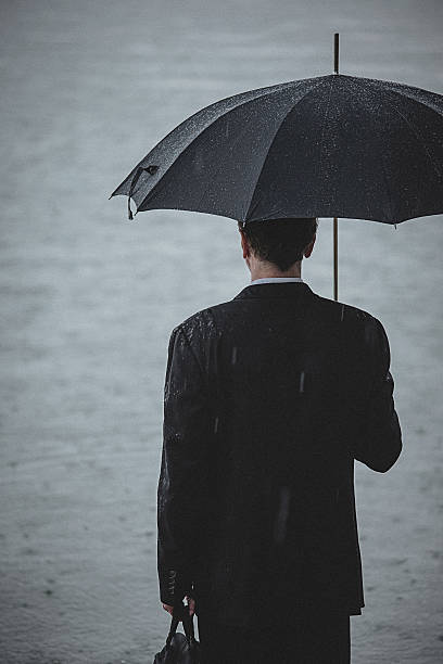 istock Handsome man wearing suit and holding umbrella during the rain 594038776