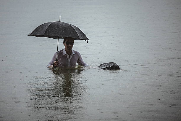 istock Handsome man wearing white shirt and holding umbrella during rain 594038828