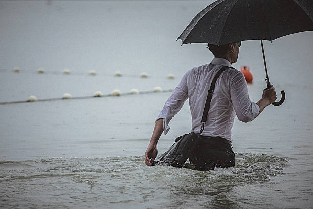 istock Handsome man wearing white shirt and holding umbrella during rain 594038866